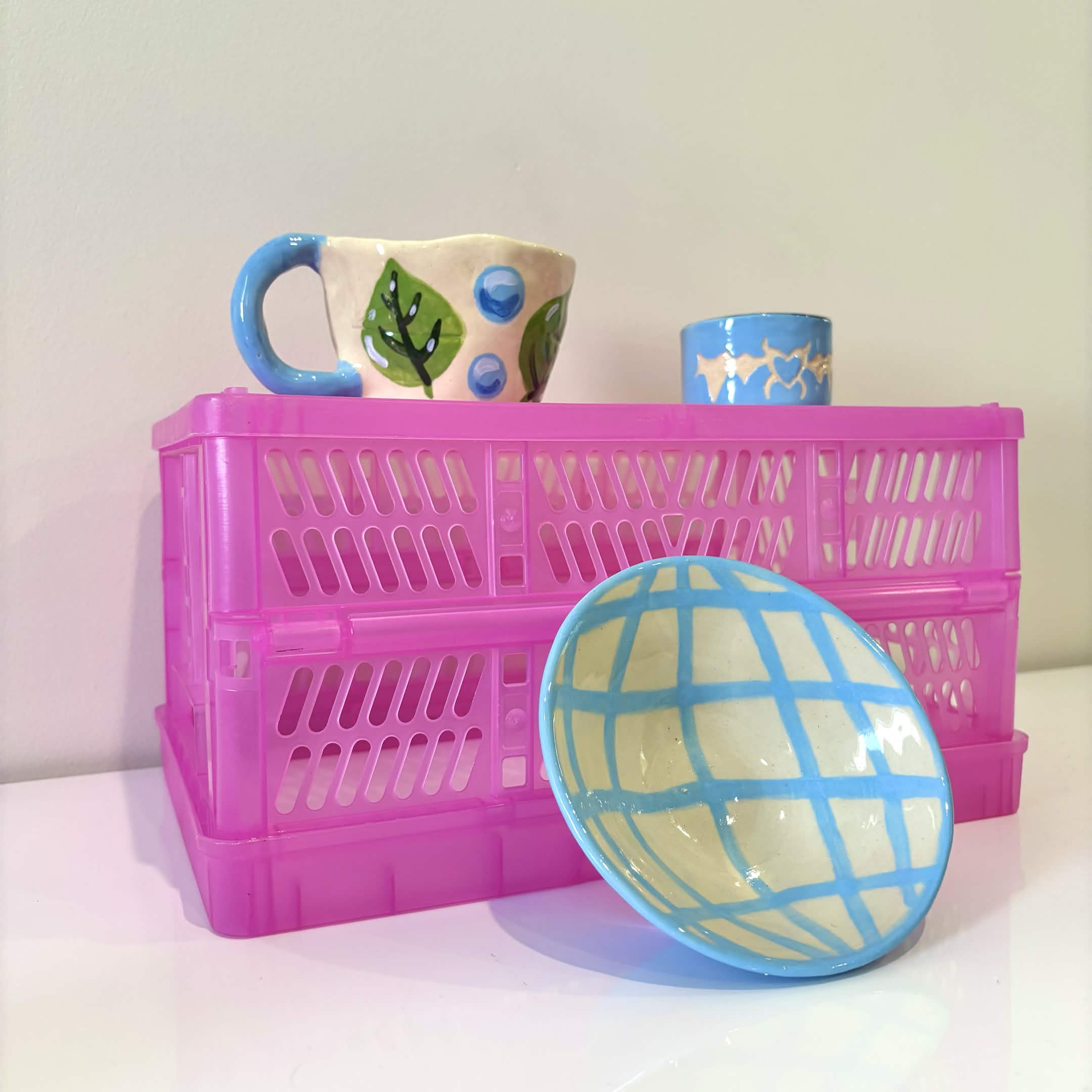 Blue handmade ceramic dish and mug displayed with pink crates